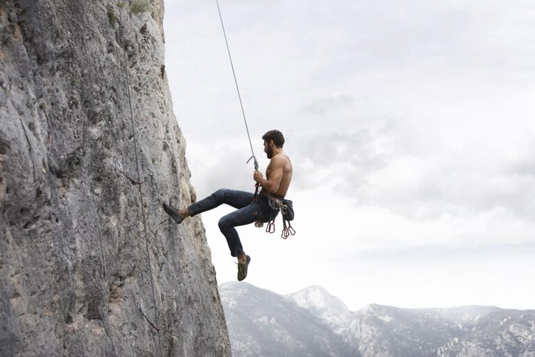 strong man climbing mountain representing pushing through self-doubt and keep going anyway