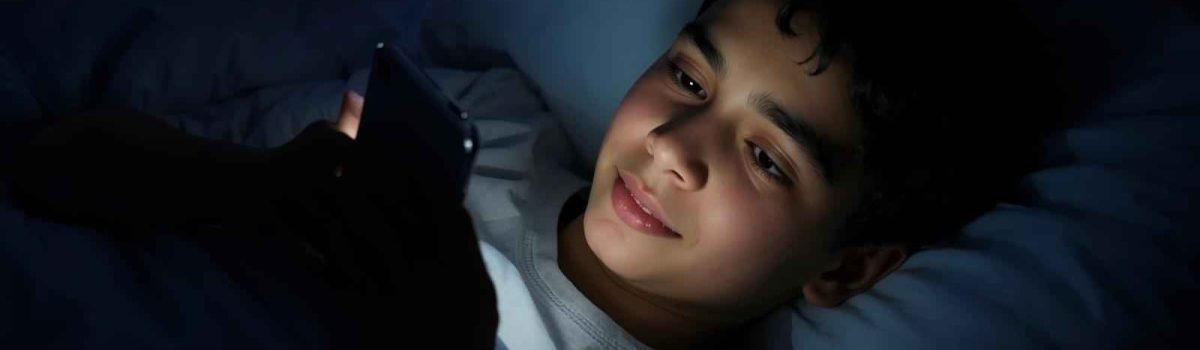 Person using smartphone in a dark room at night with screen lighting their face